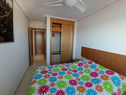 een slaapkamer met een bed met een kleurrijke sprei bij Mirador44 in Peñíscola