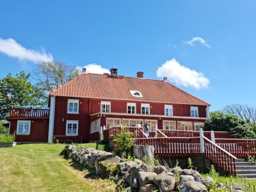 a large red house with a stone fence at Kobbar & Skär Vandrarhem in Ellös