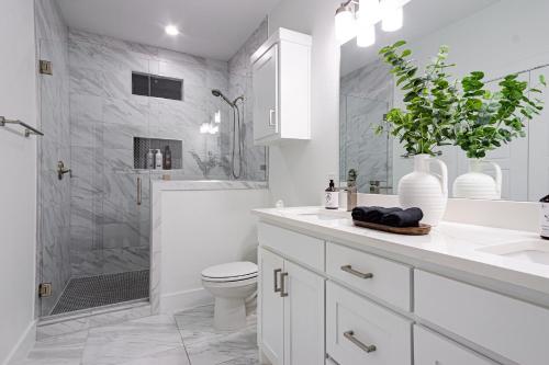 a white bathroom with a toilet and a shower at Beautiful Contemporary 4BR near Downtown Dallas in Dallas