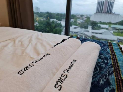 two white towels on a bed with a window at Lovely Kozi Square Studio Bedroom with Pool LV5C in Kuching