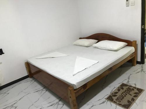 a bed with white sheets and a wooden headboard at aji fruit farm in Embilipitiya