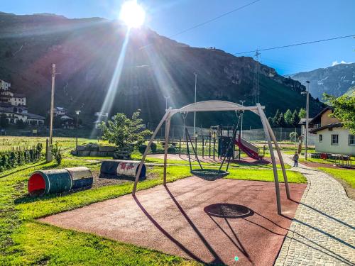a playground in a park with the sun shining at Heimelige Ferienwohnung mit Sicht in die Bergwelt in Bivio