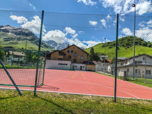 a tennis court with a fence and mountains in the background at Heimelige Ferienwohnung mit Sicht in die Bergwelt in Bivio