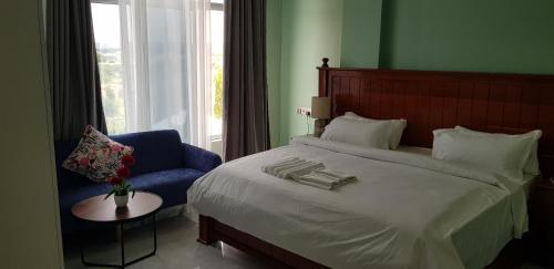 a bedroom with a large bed and a blue chair at Eastern City Hotel in Dodoma