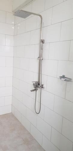 La salle de bains est pourvue d'une douche et de carrelage blanc. dans l'établissement Eastern City Hotel, à Dodoma