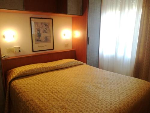 een slaapkamer met een bed met een gele sprei en een raam bij Hotel Dall'Ara in Villa Marina