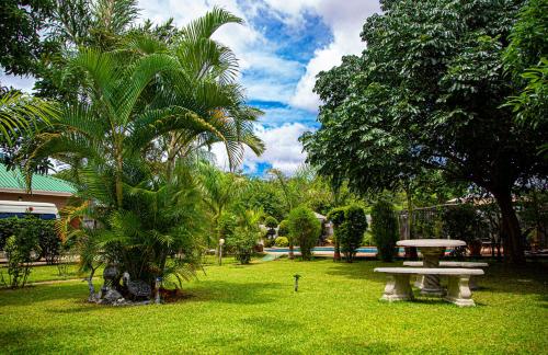 a park with a picnic table and palm trees at Dzimbahwe Guest Lodge in Victoria Falls