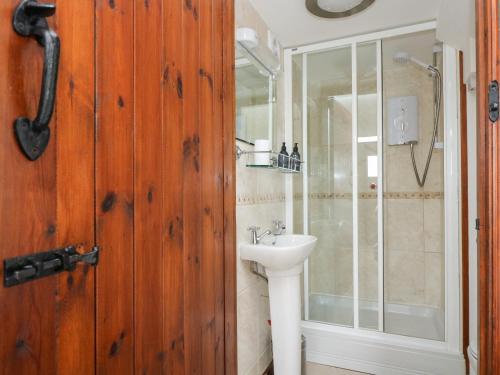 a bathroom with a sink and a glass shower at Castle Dore Barn in Par
