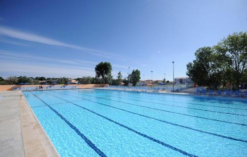 a large swimming pool with blue water at Mobil home 6 ou 8 pers Au camping Le Grau-du-Roi Domaine l'Elysée in Le Grau-du-Roi