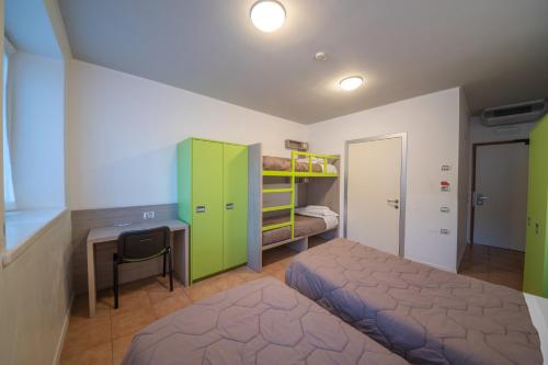 a bedroom with a bed and a desk and a bed and a bunk bed at Ostello Città di Rovereto in Rovereto