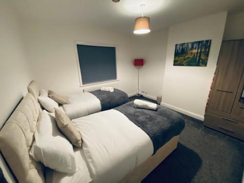 a hotel room with two beds and a flat screen tv at Kingsway Lounge - Accomodation for Nuneaton Contractors & Industrial estate - Free Parking & WIFI Sleeps up to 7 people in Nuneaton