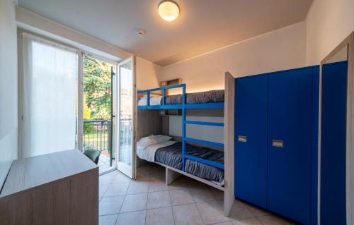1 dormitorio con literas azules y ventana en Ostello Città di Rovereto, en Rovereto
