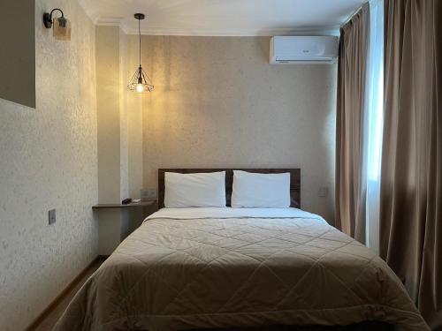 a bed with white pillows in a bedroom with a window at Moss Art Boutique Hotel in Baku