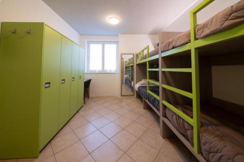 Habitación con literas verdes y pasillo. en Ostello Città di Rovereto en Rovereto