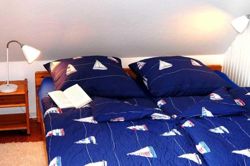 a bed with a blue comforter with pillows on it at Ahoi in Norddorf