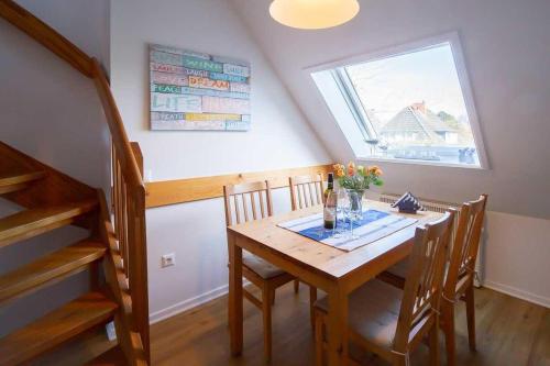 a dining room table with chairs and a window at Ahoi in Norddorf