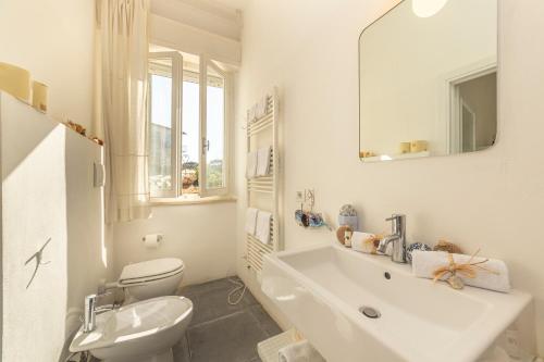 a white bathroom with a sink and a toilet at Casa Bartoli in San Vincenzo