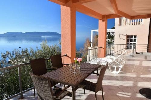 a wooden table on a balcony with a view of the water at Apartments Boženka in Klek