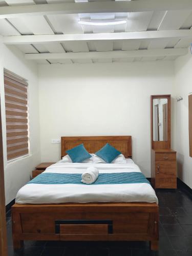 a bedroom with a large bed with blue pillows at Multiple Stories, Wayanad in Wayanad