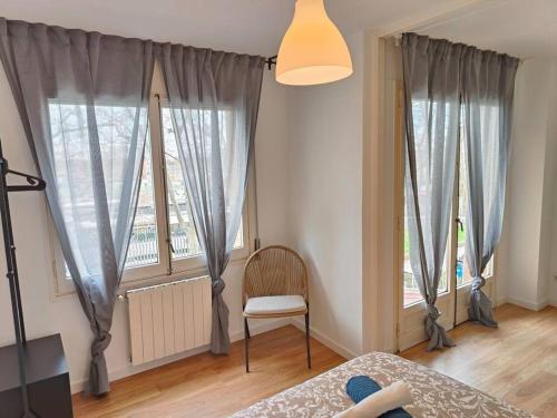 1 dormitorio con 2 ventanas, 1 silla y 1 cama en Cute apartment Sant Adria beach, en Sant Adrià de Besòs