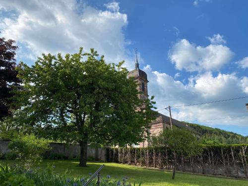 a tree in front of a building with a tower at Gîte du cerisier in Raddon-et-Chapendu