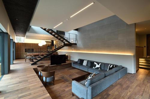 a living room with a couch and a staircase at NIVIA in Hakuba