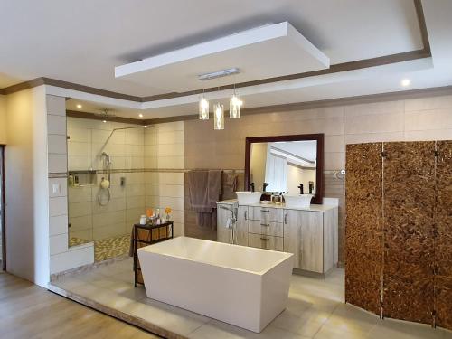 a large bathroom with a tub and a shower at Goggas Nest BNB & Restaurant in Matsapha