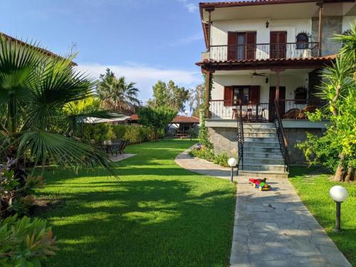 a house with a green lawn in front of it at Villa Beta - 5min walk to beach, BBQ, Parking in Pefkohori
