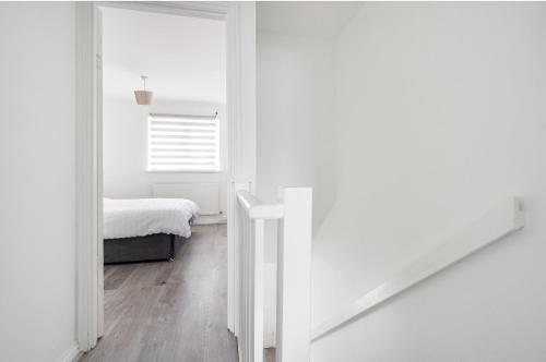 a white bedroom with a bed and a mirror at Beautiful Comfortable House in Thamesmead
