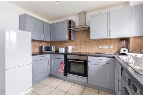 a kitchen with stainless steel appliances and white cabinets at Beautiful Comfortable House in Thamesmead