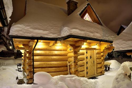 Cabaña de madera con techo cubierto de nieve en Zakopiańska Osada Domki, en Zakopane