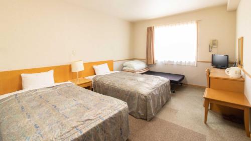 a hotel room with two beds and a television at Resort Inn Fuyo Kawaguchiko Inter in Fujiyoshida