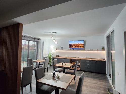 uma sala de jantar com mesas e cadeiras e uma televisão em Armina's Residence em Uisenteş