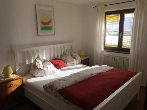- une chambre dotée d'un lit blanc avec des draps et des oreillers rouges dans l'établissement Ferienwohnung Meindl Elfi An der Drachenwand 44, à Mondsee