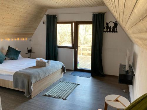 a bedroom with a bed and a large window at Cabanele lu’ Dinu in Curtea de Argeş