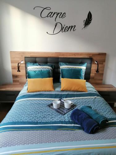 a bed with two cups and a sign that reads caredn at Gîte d'EU la Rivière à la Mer in Eu