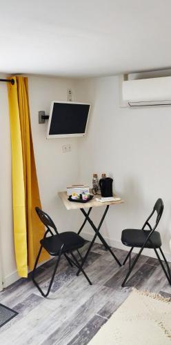 a table and two chairs in a room with a tv at Les Gones en Vendée in Saint-Gervais