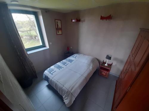 ein kleines Schlafzimmer mit einem Bett und einem Fenster in der Unterkunft Gîte Le Chant des Cloches in Fleurey
