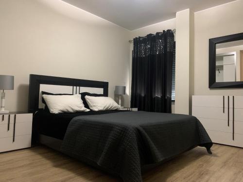 a bedroom with a black bed and a mirror at Giesta Flower by Madeira Holiday Rentals in Ribeira Brava