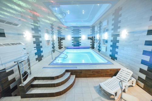 a swimming pool in a room with stairs and a tub at SPA Villa Jasmin in Truskavets