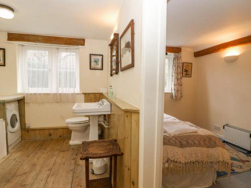 uma casa de banho com uma cama, um lavatório e um WC. em Brooklands em Chedworth