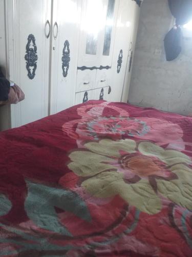 Una cama con una manta roja con una flor. en snial hoom en Rafaḩ