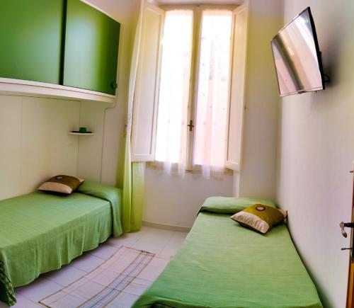 two green beds in a room with a window at Villa catalana al centro di Alghero in Alghero