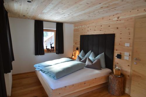 een slaapkamer met een bed met een houten muur bij Lüch dl Finatzer in San Martino in Badia