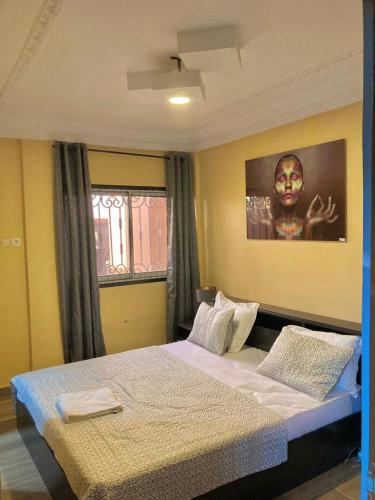 a bedroom with a bed and a picture of a woman at At Home Lisda in Yaoundé