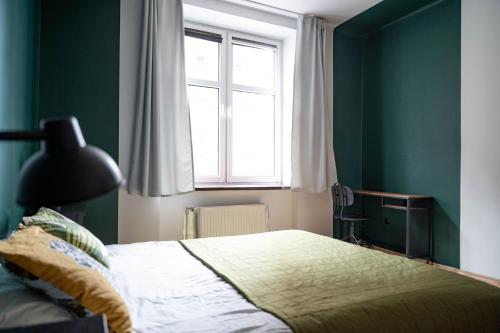 Apartament blisko Starego Miasta في غدانسك: غرفة نوم بجدران خضراء وسرير مع نافذة