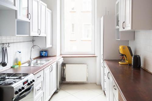 Apartament blisko Starego Miasta في غدانسك: مطبخ بدولاب بيضاء ومغسلة ونافذة