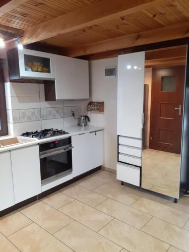 a kitchen with white appliances and a wooden ceiling at Domek nad jeziorem in Klepnica