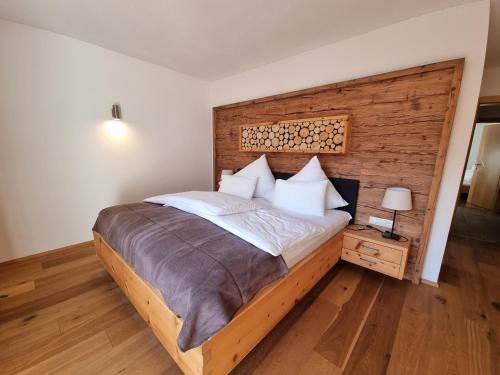 a bedroom with a large bed and a wooden wall at Ferienlandhaus Höfer in Fulpmes