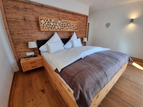 ein Schlafzimmer mit einem großen Bett und einer Holzwand in der Unterkunft Ferienlandhaus Höfer in Fulpmes